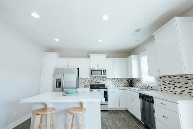 kitchen featuring appliances with stainless steel finishes, a sink, backsplash, and a kitchen island