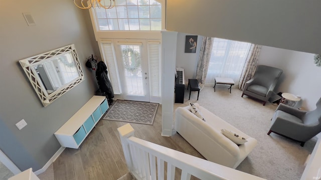 entryway featuring baseboards, wood finished floors, a towering ceiling, and an inviting chandelier