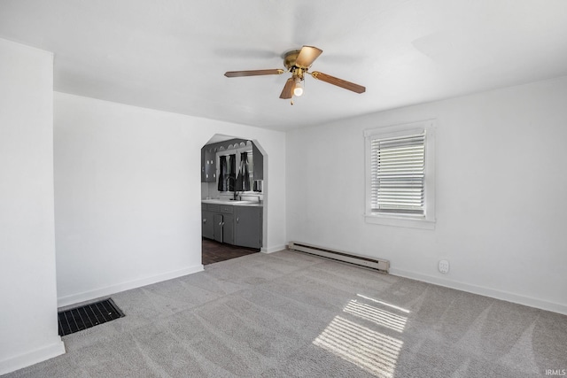 carpeted empty room with visible vents, arched walkways, a ceiling fan, baseboards, and a baseboard radiator