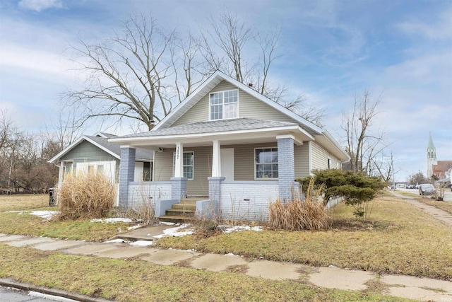 bungalow with covered porch and brick siding