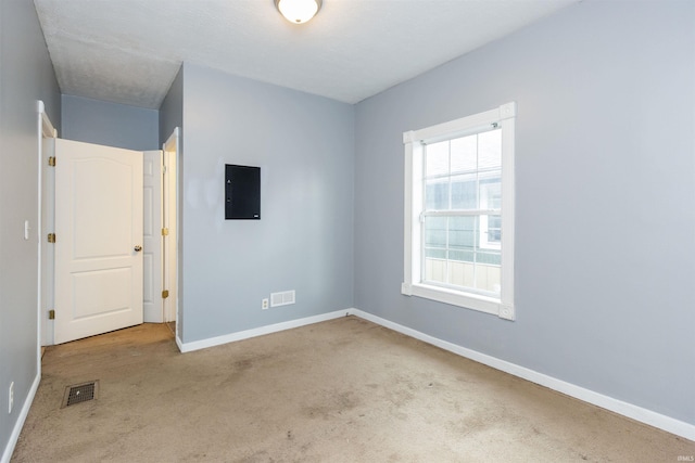 unfurnished bedroom with baseboards, carpet flooring, visible vents, and electric panel