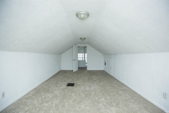 bonus room with visible vents, carpet flooring, vaulted ceiling, and a textured ceiling