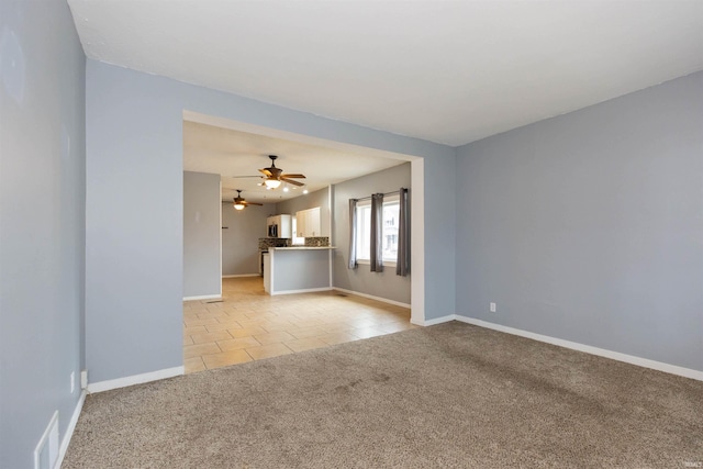 unfurnished living room with light tile patterned floors, baseboards, visible vents, light colored carpet, and ceiling fan