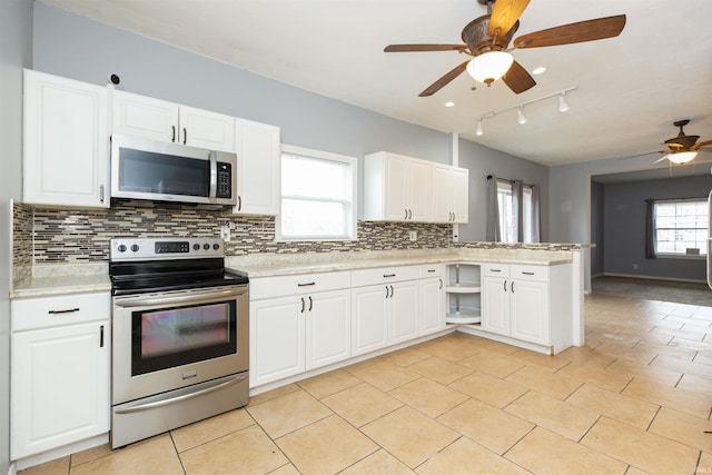 kitchen with a peninsula, appliances with stainless steel finishes, light countertops, and decorative backsplash