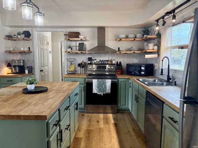 kitchen with wall chimney range hood, butcher block counters, stainless steel appliances, and green cabinetry