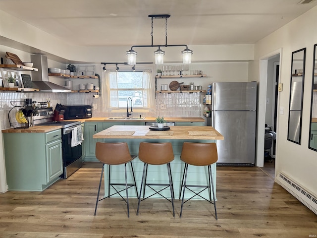 kitchen with a baseboard heating unit, stainless steel appliances, butcher block countertops, a sink, and open shelves