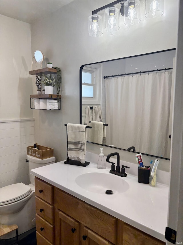 full bathroom featuring a wainscoted wall, toilet, tile walls, and vanity