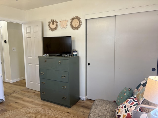 bedroom with a closet, light wood-style flooring, and baseboards