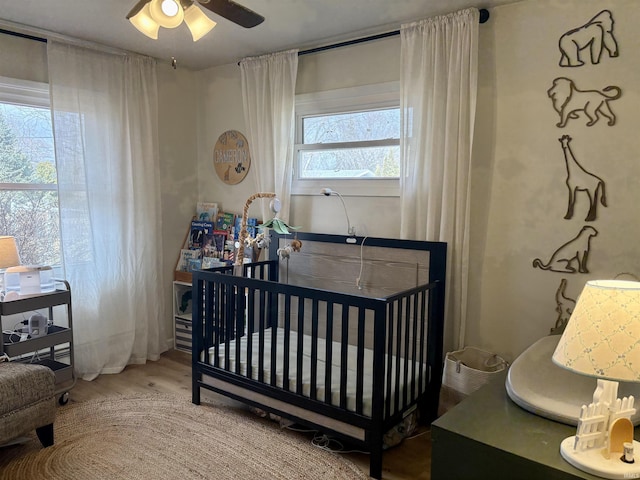 bedroom with a nursery area and wood finished floors