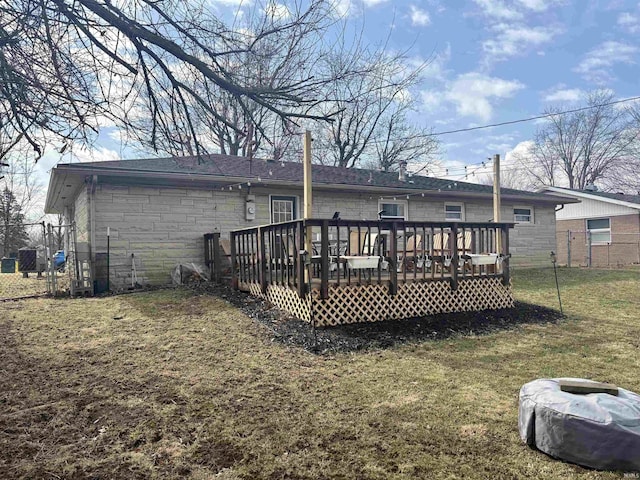 back of house featuring stone siding, a wooden deck, fence, and a yard