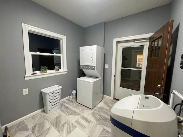 bathroom featuring baseboards and stacked washer and clothes dryer