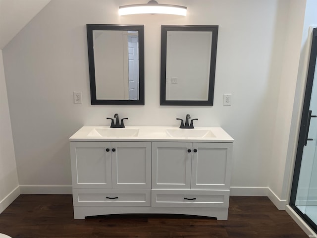 bathroom with double vanity, a sink, baseboards, and wood finished floors