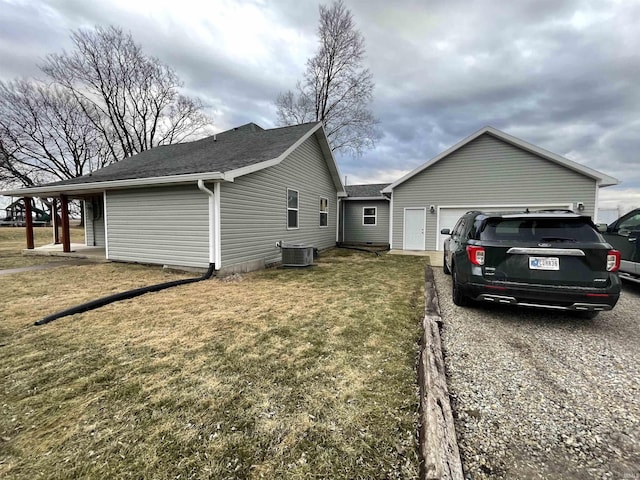 view of home's exterior featuring roof with shingles, a yard, an attached garage, central AC unit, and driveway