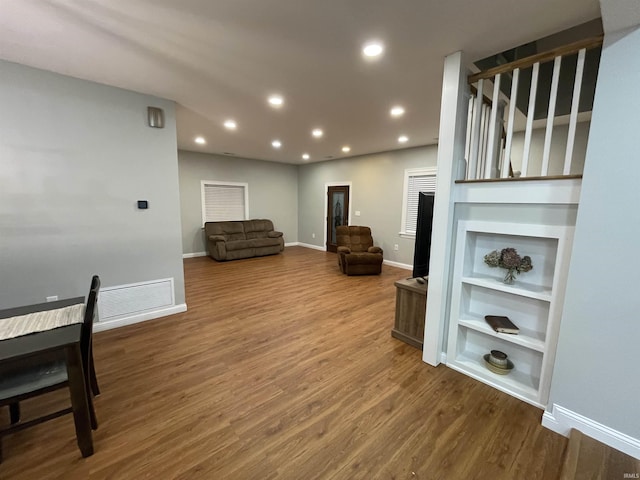 living area featuring built in shelves, recessed lighting, visible vents, wood finished floors, and baseboards