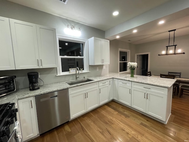 kitchen featuring stainless steel appliances, wood finished floors, a peninsula, and a sink