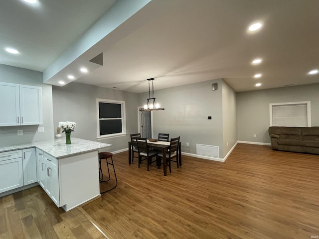 kitchen featuring light stone counters, dark wood-style flooring, recessed lighting, visible vents, and a peninsula