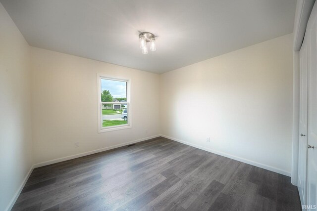 empty room featuring baseboards and dark wood finished floors