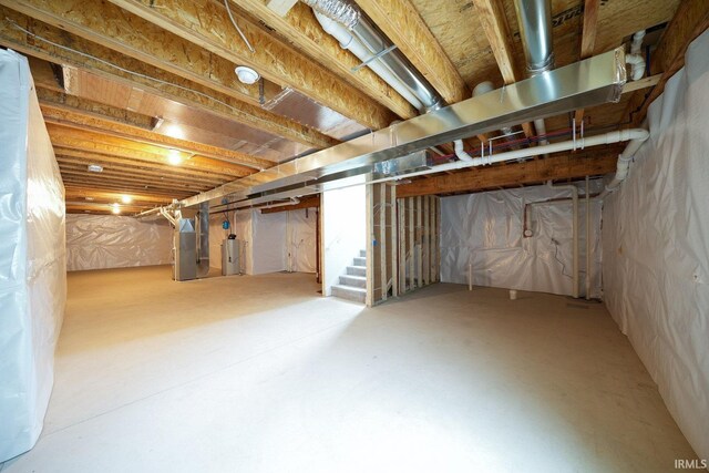 unfinished basement featuring water heater, stairway, and heating unit