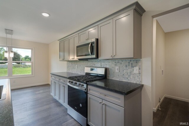 kitchen with dark wood-type flooring, gray cabinets, stainless steel appliances, and decorative backsplash