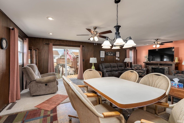 dining space featuring a wealth of natural light, light carpet, a fireplace, and wooden walls