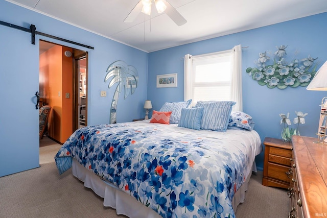 carpeted bedroom featuring a barn door and a ceiling fan