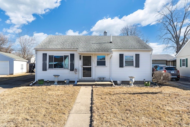 bungalow-style home with a shingled roof, a chimney, and a front lawn