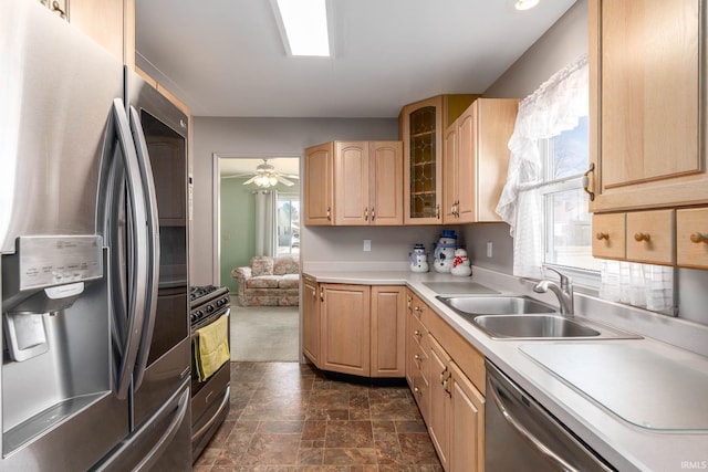 kitchen with glass insert cabinets, stainless steel appliances, light countertops, light brown cabinets, and a sink