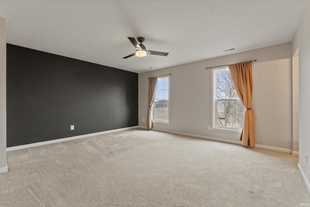 carpeted spare room with ceiling fan, a textured ceiling, visible vents, and baseboards