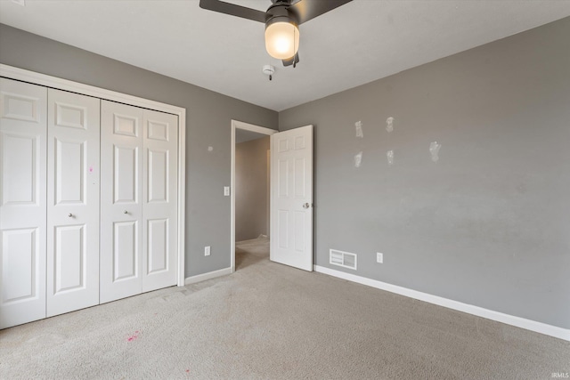 unfurnished bedroom with carpet, a closet, visible vents, a ceiling fan, and baseboards