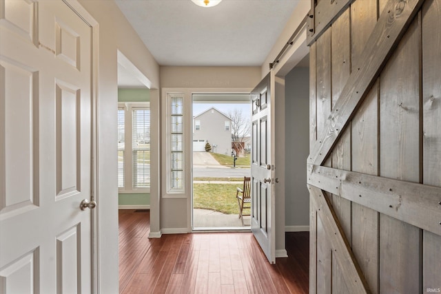 doorway with dark wood-style floors, baseboards, and a barn door