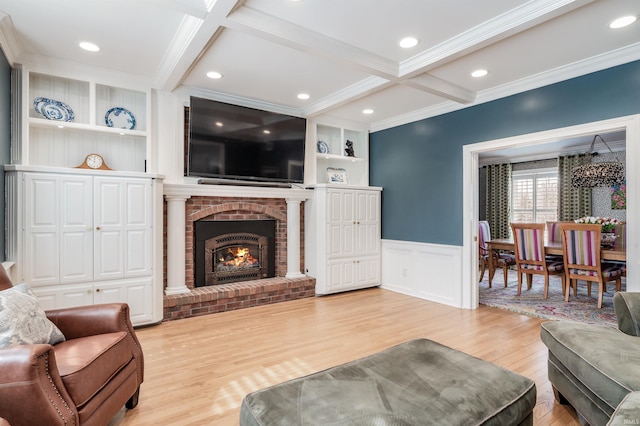 living area with built in shelves, light wood-style floors, wainscoting, and beamed ceiling