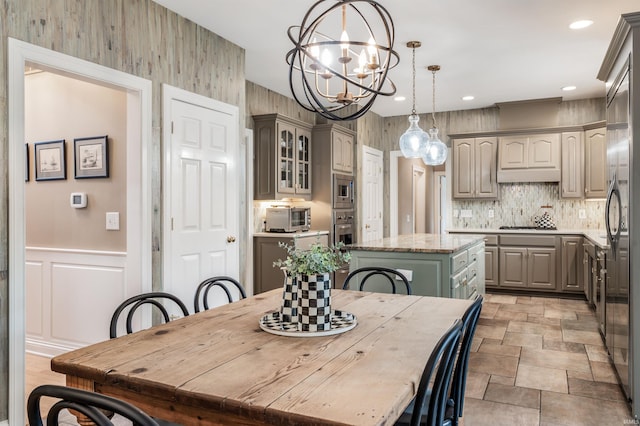 dining area featuring a decorative wall, a wainscoted wall, recessed lighting, stone finish floor, and an inviting chandelier