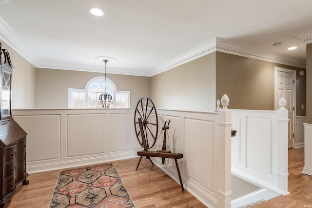 interior space featuring crown molding, recessed lighting, an inviting chandelier, light wood-style floors, and wainscoting