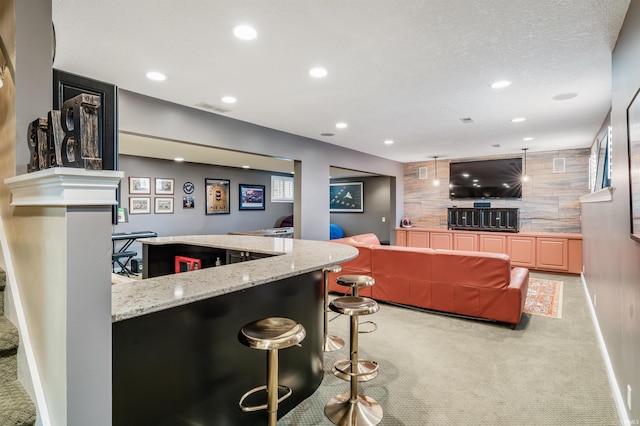 kitchen with visible vents, light colored carpet, an accent wall, a kitchen bar, and recessed lighting