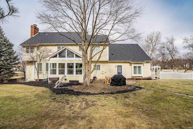 back of house featuring a sunroom, a chimney, fence, and a yard