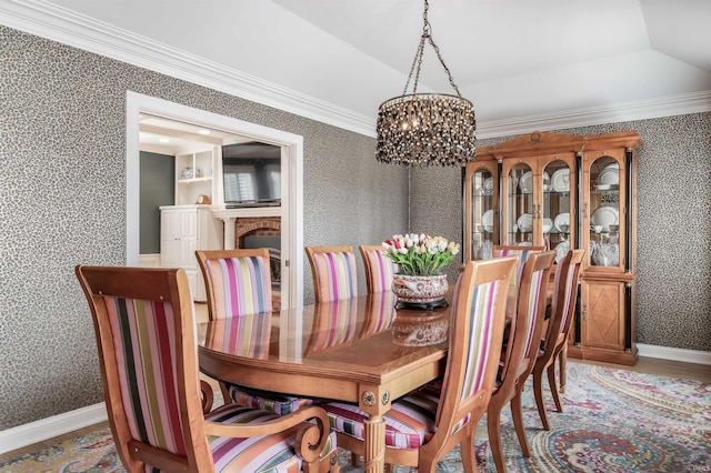 dining area with baseboards, ornamental molding, a brick fireplace, and wallpapered walls