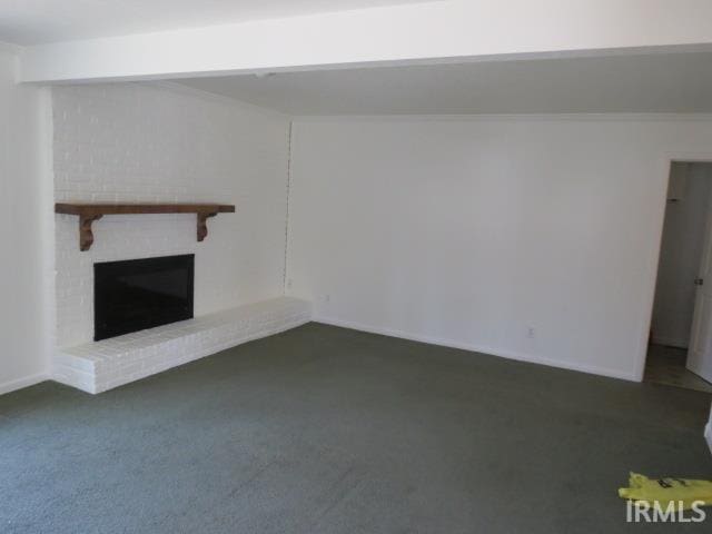 unfurnished living room featuring dark carpet, beamed ceiling, and a fireplace