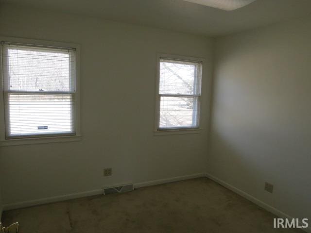 carpeted spare room with visible vents and baseboards