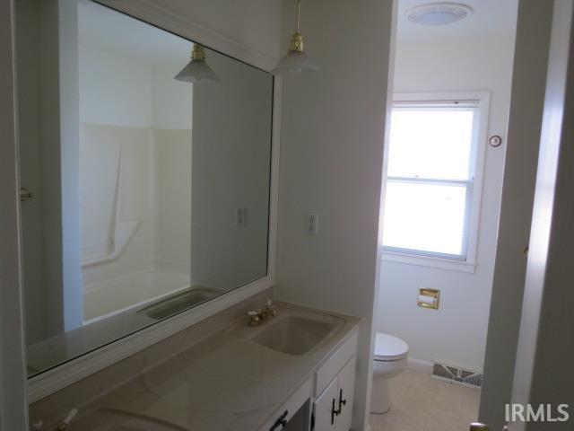 bathroom with double vanity, baseboards, visible vents, toilet, and a sink