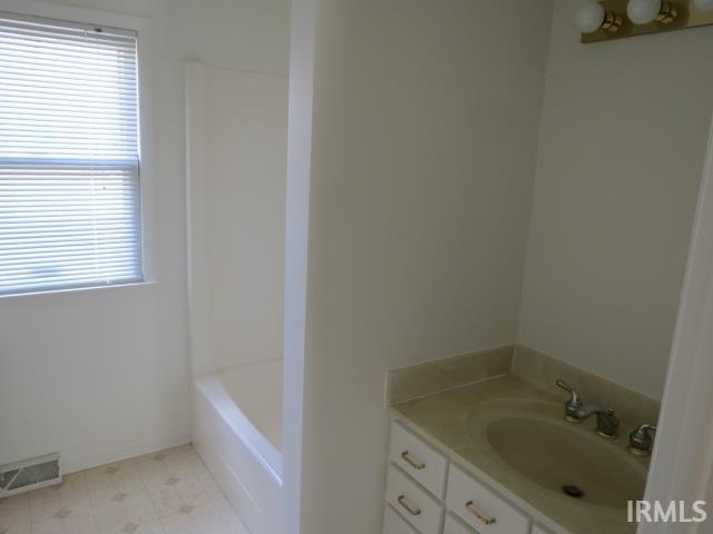 full bathroom with visible vents, a bathing tub, vanity, walk in shower, and tile patterned floors