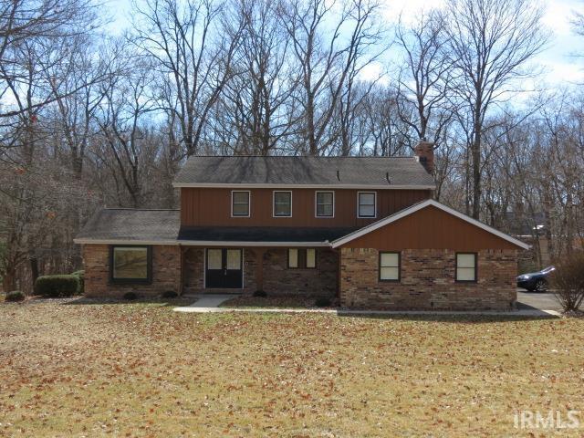 traditional-style house featuring brick siding, a chimney, and a front yard