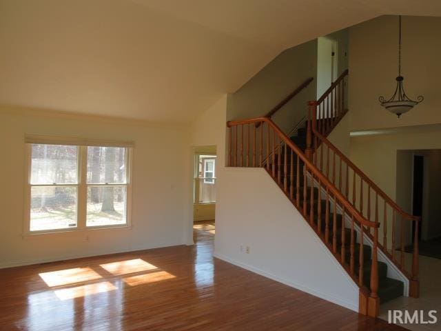 unfurnished living room with high vaulted ceiling, stairway, and wood finished floors