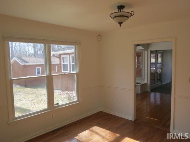 spare room with visible vents, baseboards, and wood finished floors