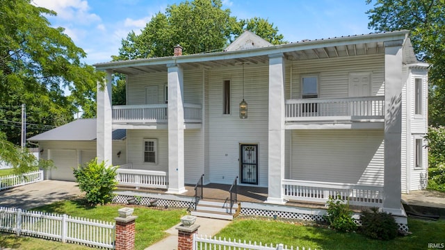 view of front of home with a balcony, a fenced front yard, a garage, and a porch