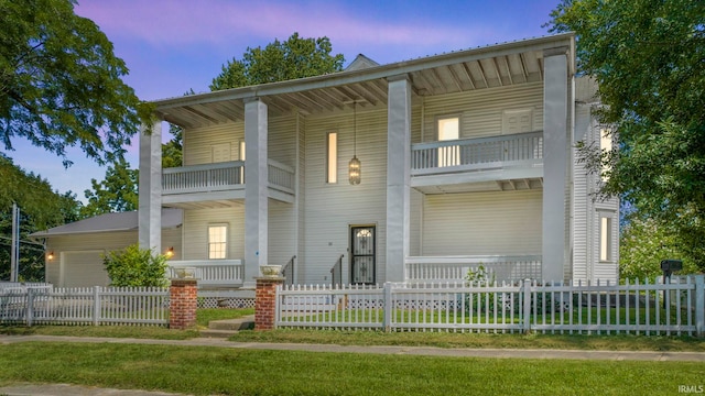 view of front facade with a balcony, a fenced front yard, and a garage