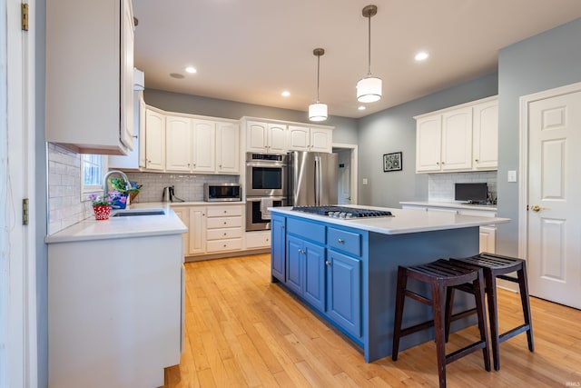 kitchen featuring blue cabinets, a sink, white cabinetry, appliances with stainless steel finishes, and a center island