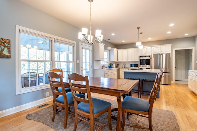 dining space with light wood finished floors, recessed lighting, visible vents, and baseboards