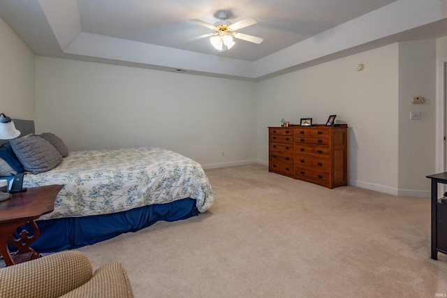 bedroom featuring light carpet, ceiling fan, baseboards, and a raised ceiling