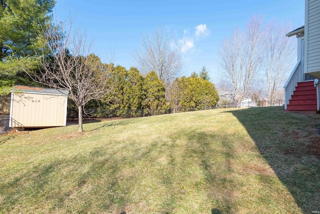 view of yard featuring an outbuilding, a storage shed, and stairs