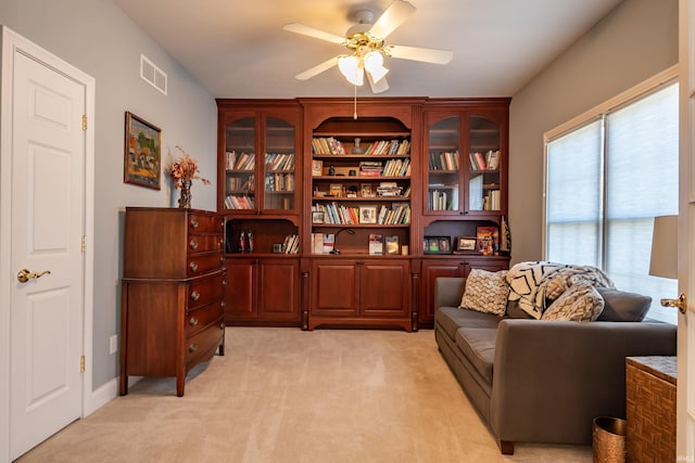 sitting room featuring a ceiling fan, visible vents, and light colored carpet